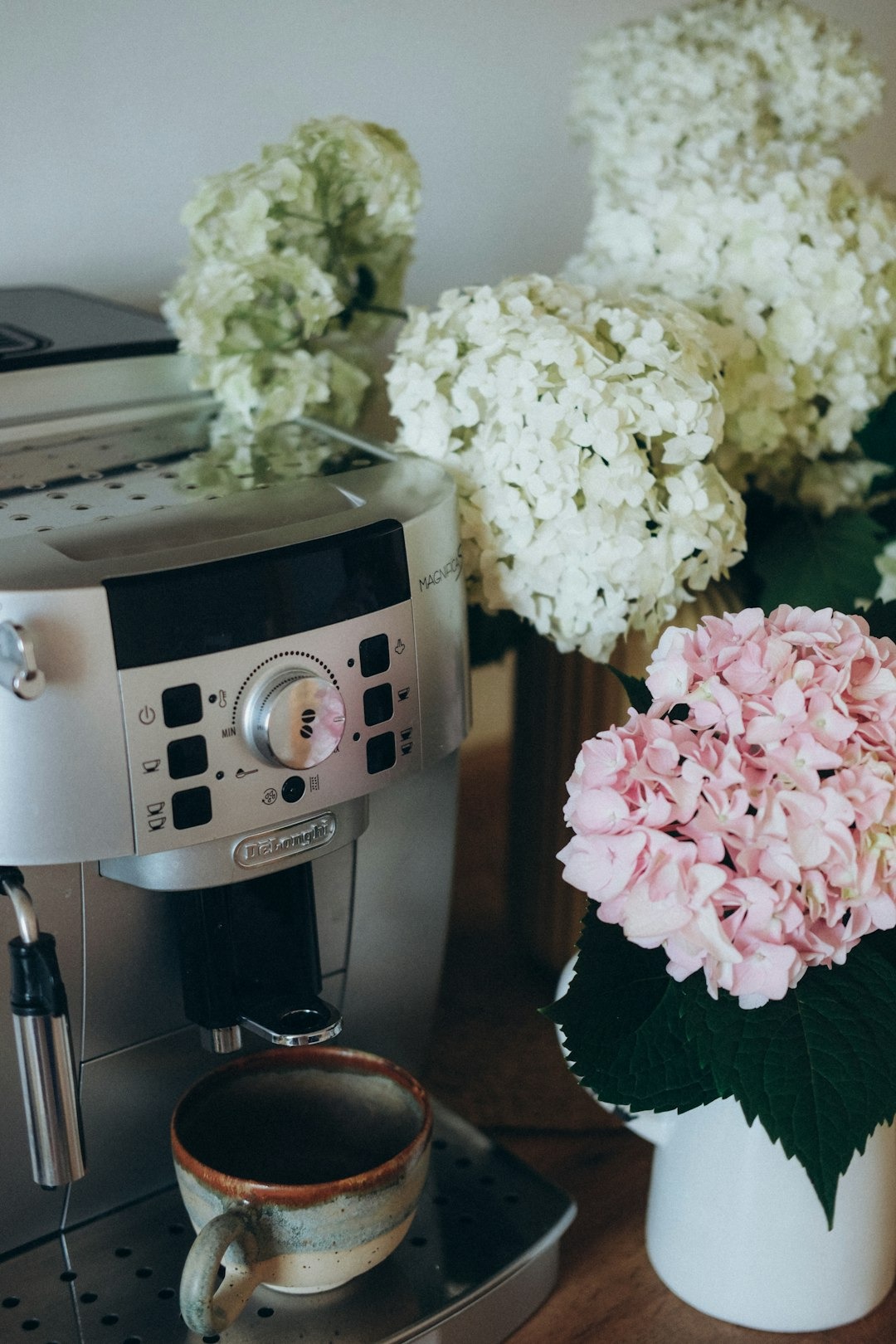 A silver espresso machine dispenses coffee into a ceramic cup.